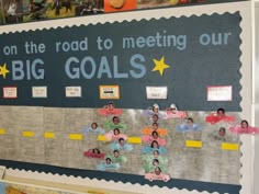 a bulletin board with people on the road to meeting our big goals written on it