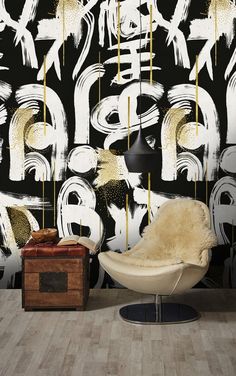 a chair and ottoman in front of a black wall with gold paint splattered on it