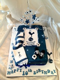 a soccer themed birthday cake is displayed on a white cloth covered tablecloth with blue and white decorations