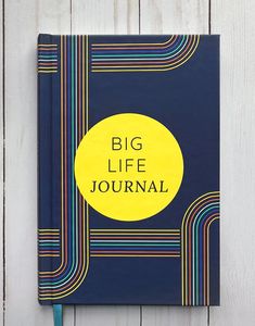 a blue notebook with the words big life journal written on it, against a white wooden background