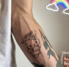 a person with a hello kitty tattoo on their left arm and the rainbow in the background