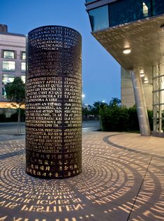 a large metal object sitting in the middle of a sidewalk next to a tall building