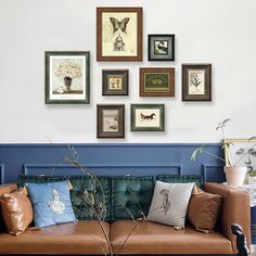 a living room filled with lots of framed pictures on the wall above a brown couch