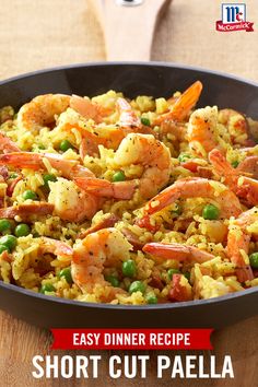 a pan filled with shrimp and rice on top of a wooden table