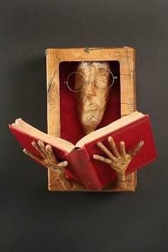 a wooden box with an open book in the shape of a hand holding a red book