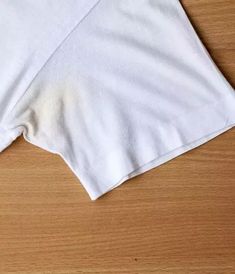 two white t - shirts sitting on top of a wooden table next to each other