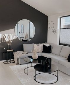 a modern living room with black and white decor on the walls, round mirror above the couch