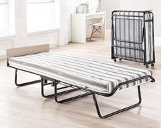 two folding beds in the middle of a room with white walls and wood flooring