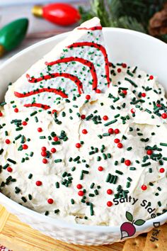 a bowl filled with white frosting and sprinkles next to crackers