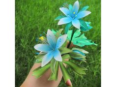 a hand holding three blue flowers in it's palm