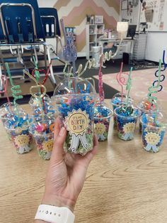 someone is holding up some cupcakes in front of the birthday candles on display