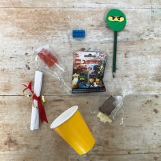 some legos are sitting on the table next to a plastic cup and other items