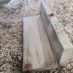 a piece of wood that is laying on some shavings in the floor area