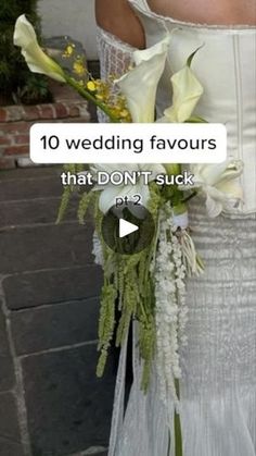 a woman in a wedding dress holding a bouquet with flowers on it's side