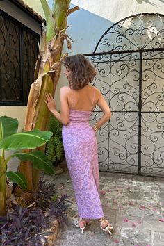 a woman in a purple dress standing next to a tree