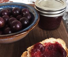 plum jam in a glass jar next to a bowl of plums