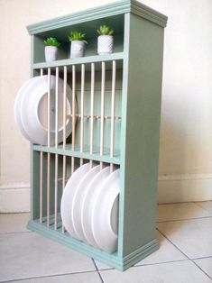 a green shelf with plates and cups on it, sitting in front of a wall