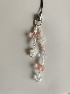 a necklace with beads and charms hanging from it's side on a white surface