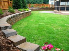 a backyard with grass and stone steps leading up to the back yard