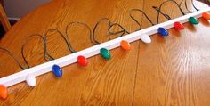 a wooden table topped with a name sign and string lights on the end of it