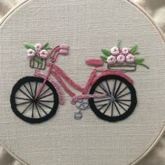 a close up of a embroidery on a hoop with a bike and flowers in it