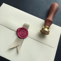 a wax stamp on top of an envelope with a ribbon around it and a wax seal next to it