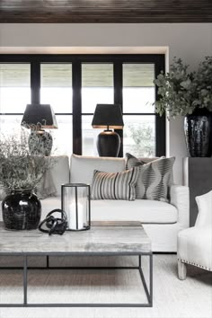 a living room filled with white couches and black vases on top of a coffee table