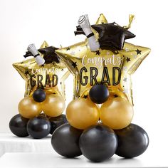 some black and gold balloons are in the shape of stars with congratulations written on them