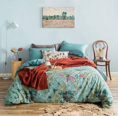 a bedroom with a bed covered in blue and green sheets, pillows and blankets on it