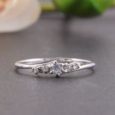 a three stone diamond ring sitting on top of a table next to an onion plant