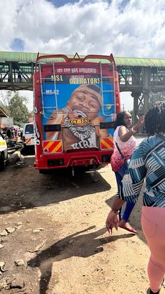 a woman and child are standing in front of a bus with an ad on it