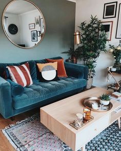 a living room with a blue couch and coffee table in front of a round mirror