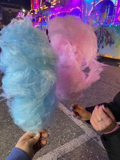 two people are holding cotton candy in their hands