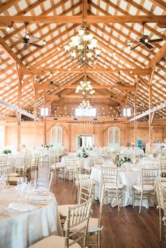 the inside of a large wooden building with tables and chairs set up for an event