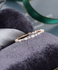 a diamond ring sitting on top of a purple pillow next to a pair of glasses