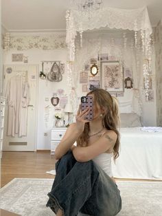 a woman sitting on the floor taking a selfie with her cell phone in front of her