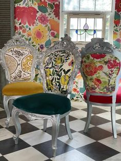 four colorful chairs sitting on top of a checkered floor