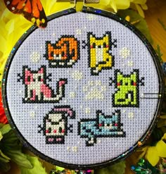 a cross - stitch pattern with cats and flowers on the table next to yellow flowers