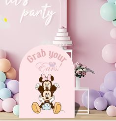 there is a pink backdrop with balloons and a minnie mouse sign on the floor in front of it