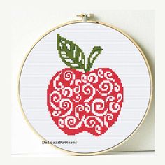 a cross stitch pattern with a red apple on it's side and green leaves in the middle