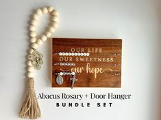 a wooden sign that says our life our sweetness is our hope and beads are hanging on the wall