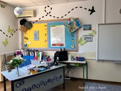 a classroom with a whiteboard, desks and decorations on the wall in front of it