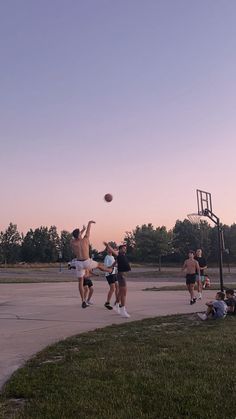 some people are playing basketball on a court at sunset or dawn with the sun going down