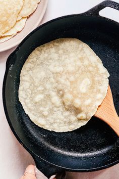 a skillet with food cooking in it on a table next to plates and utensils