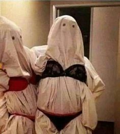 two women dressed in ghost costumes standing next to each other with their hands on their hipss