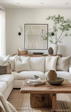 a living room filled with white furniture and lots of pillows on top of the couch