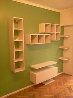 an empty room with green walls and white shelves