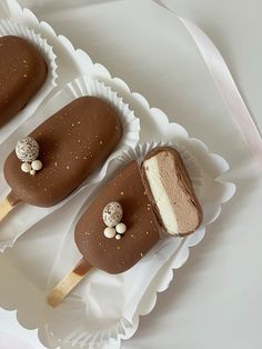 three chocolate covered desserts sitting on top of paper plates