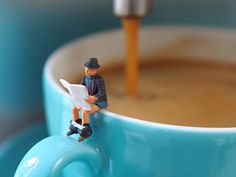 a toy man sitting on top of a coffee cup