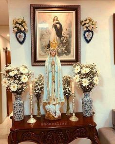 the statue is surrounded by vases with flowers and candles in front of it on a table